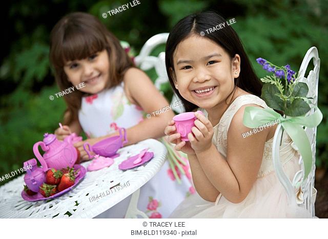 Mixed race girls having tea party in backyard
