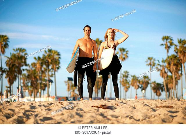Surfing couple with surfboards looking out from Venice Beach, California, USA