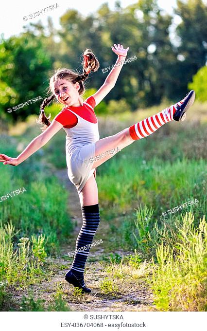 A funny cute outdoor portrait of a little girl presenting Pippi Longstocking and showing out out her tongue