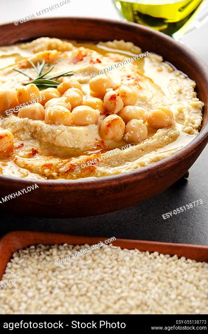 Closeup view at Hummus topped with beans olive oil and green rosemary leaves on kitchen table