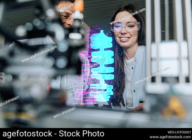 Smiling female and male engineers examining futuristic automation at laboratory