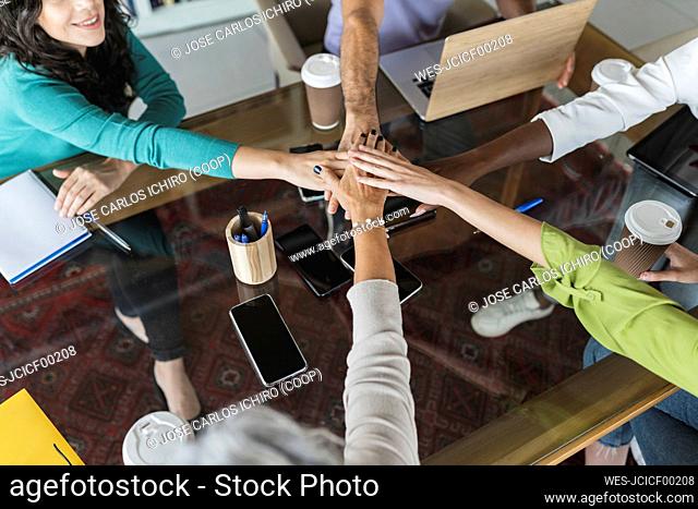 Business colleagues stacking hands together in office