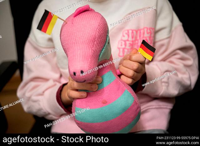 23 November 2023, Berlin: Eight-year-old Elsa holds a stuffed seahorse with German flags during a ceremony in the Berlin House of Representatives for...