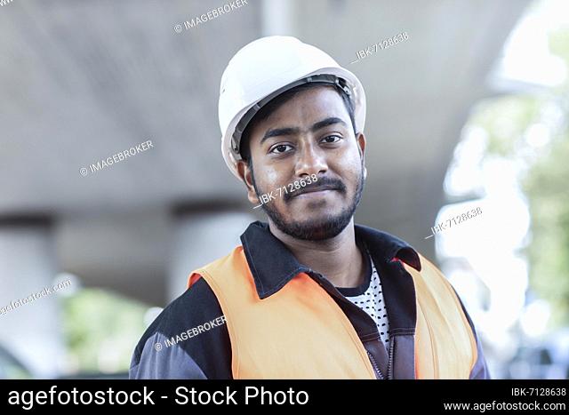 Young technician with beard outside with helmet working on a bridge, Baden-Württemberg, Germany, Europe
