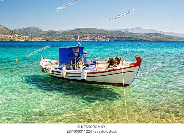 Moored fishing boat in the clear water of the sea on a background of mountains
