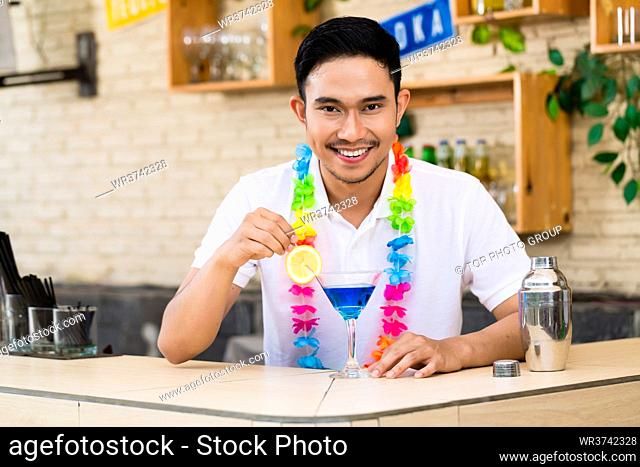 Portrait of a bartender stirring blue cocktail in bar