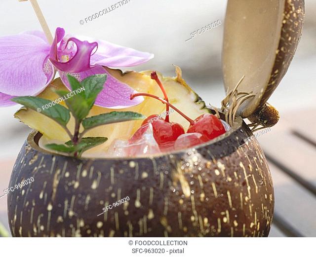 Coconut drink with pineapple, cocktail cherry and orchid