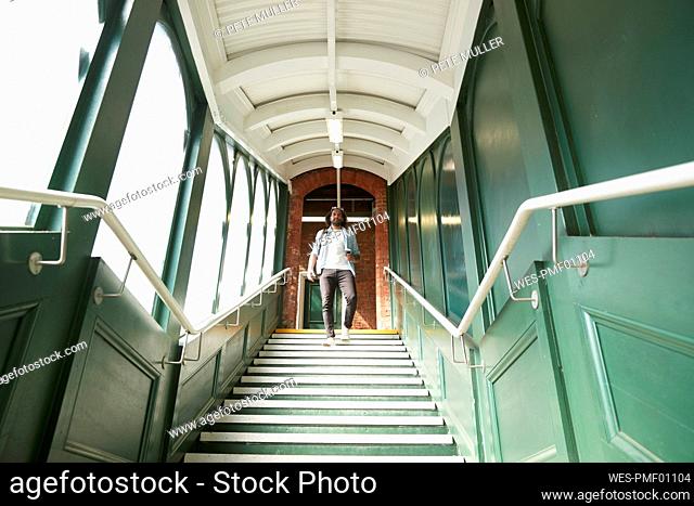 Young trendy man moving down steps at railroad station