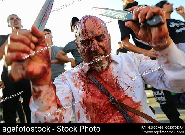 09 August 2022, Iraq, Baghdad: A Shiite Muslim man hits his head with swords, known as Tatbir, during a ritual ceremony on the day of Ashura in Tahrir Square in...