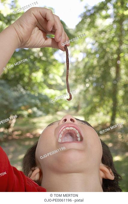Young boy outdoors eating an earthworm