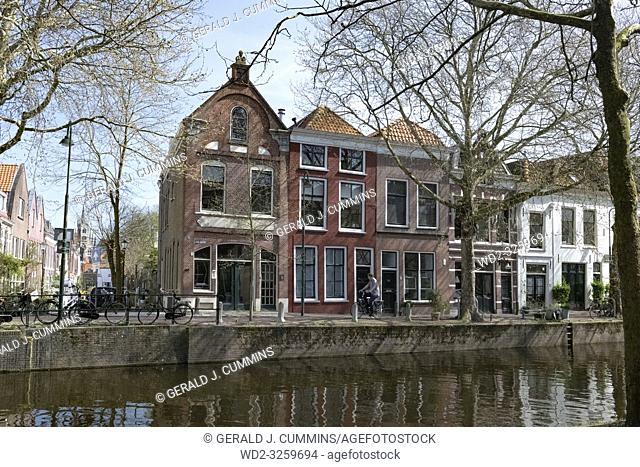 Netherlands, Gouda, 2017, cyclist passing in front of traditional houses on the banks of a canel