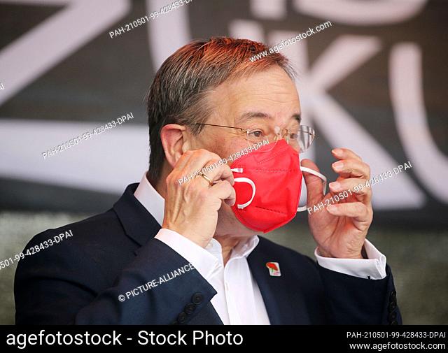 01 May 2021, North Rhine-Westphalia, Duesseldorf: Armin Laschet (CDU), Minister President of North Rhine-Westphalia, takes off a red mask at the May Day rally