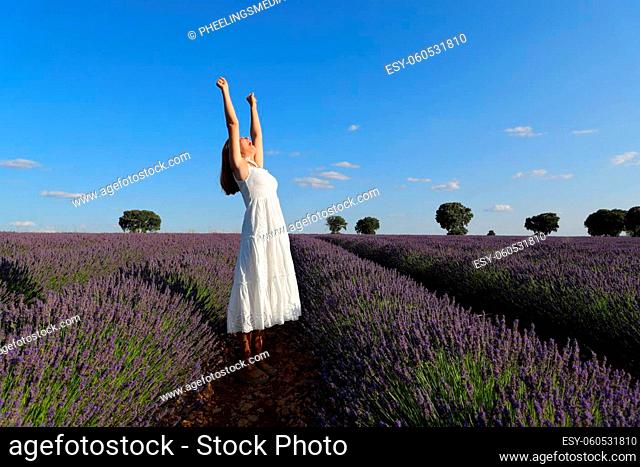 Excited woman celebrating raising arms in a lavender field