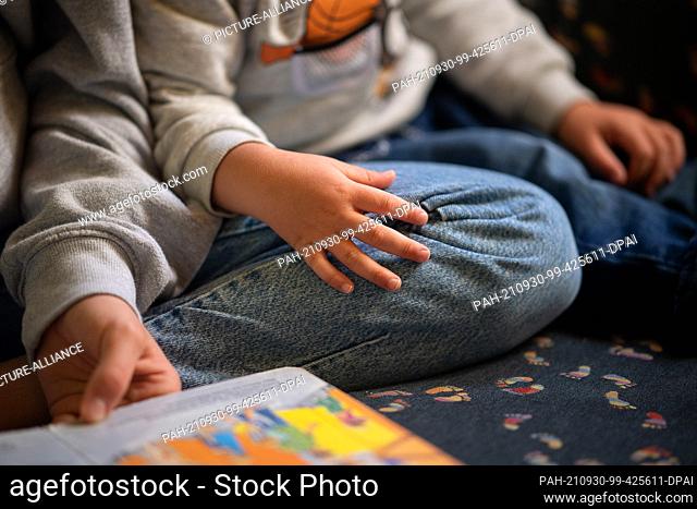 30 September 2021, Hessen, Marburg: A trainee reads to children at a daycare center during a Social Day organized by the aid organization Schüler Helfen Leben