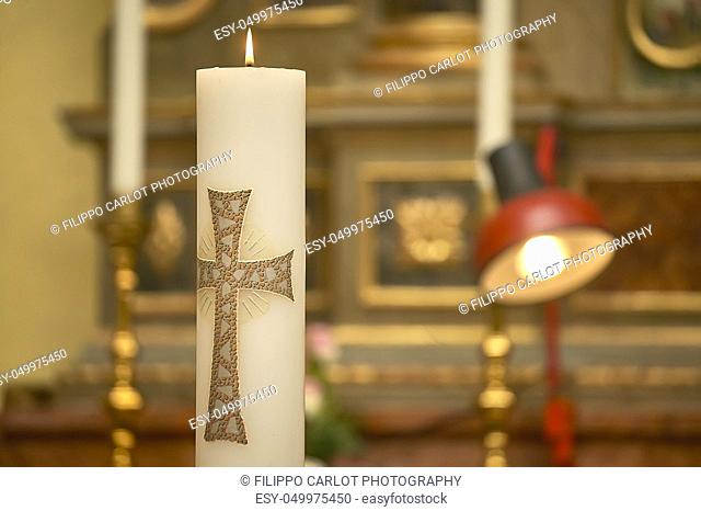 Horizontal shot of an Easter candle with the cross lit in the church during the ceremony of a baptism