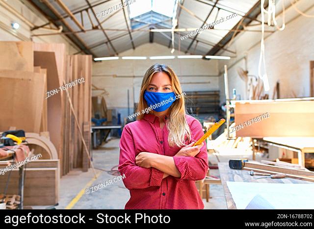 Frau als Handwerker Lehrling mit Mundschutz wegen Covid-19 in der Werkstatt