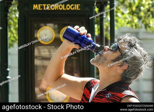 A cyclist refreshes himself as the thermometer shows 34 degrees Celsius at the meteorological station in front of the Beseda in the centre Pilsen