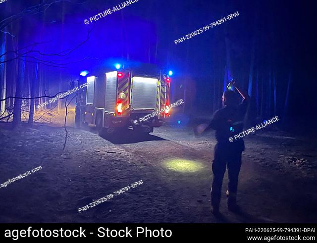 25 June 2022, Brandenburg, Kosilenzien: Firefighters gather at night during their mission in the burned forest near Kosilenzien