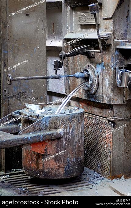 Gießerei: Flüssiges Aluminium fließt in einen Tiegel