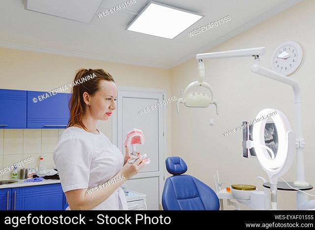 Female dentist showing dentures toward live streaming smart phone