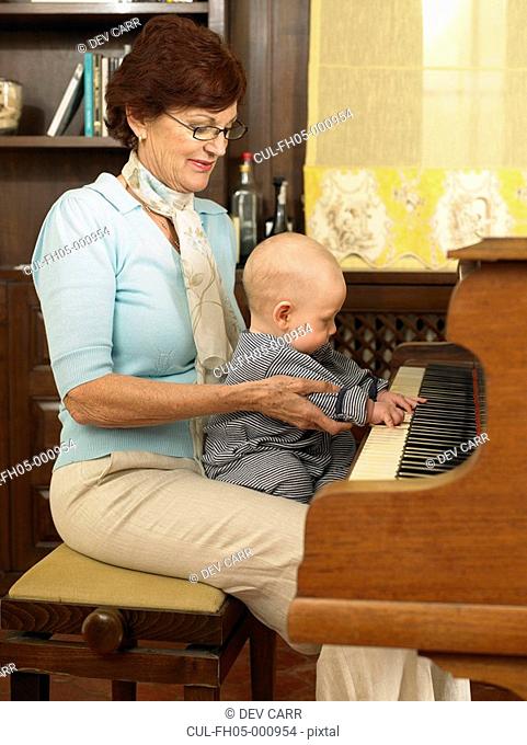 Senior grandmother playing piano with baby grandson 1-3 months