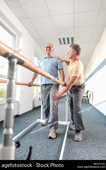 Physiotherapist woman helping senior man in rehabilitation walking on the bars