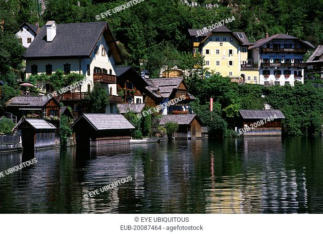 Typical architecture and boat houses on shore of Hallstattersee Lake and reflected in rippled surface