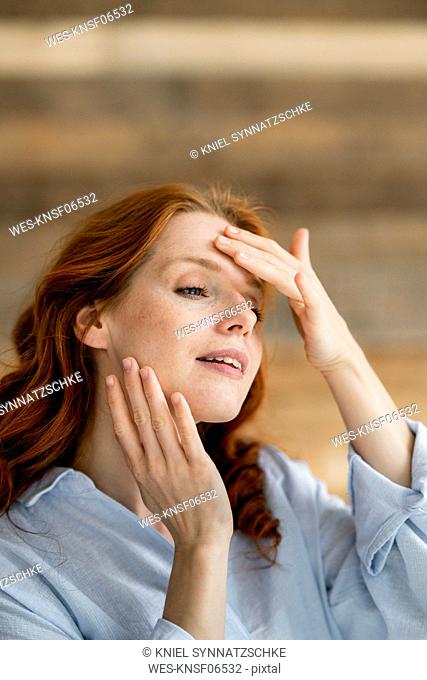 Portrait of redheaded woman touching her face