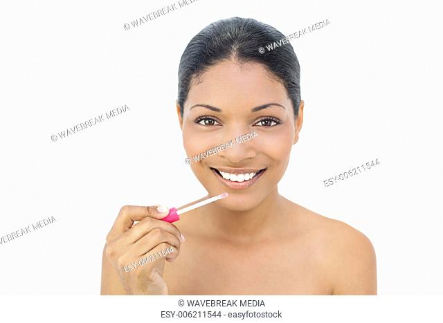 Smiling black haired model applying lip gloss