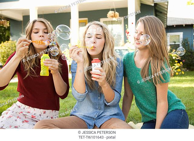 Portrait of three friends blowing bubbles