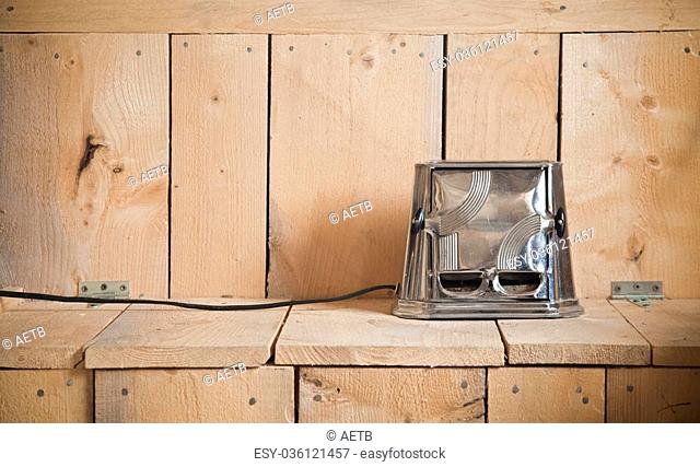 Old classic toaster on a nice cedar plank of wood texture. Warm and calm ambiance. Using ambient light (sunlight), it gives to this image a more natural look