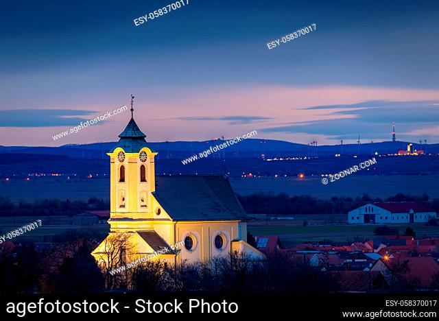 church of village of Oggau at lake Neusiedlersee before sunrise with lights