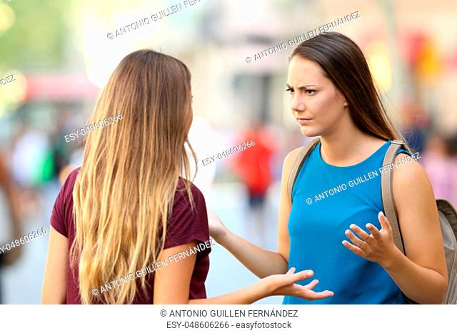 Two angry friends having a serious conversation outdoors on the street