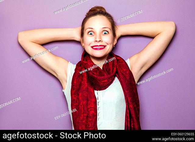 Surprised Woman. Young emotional beauty with collected hair and red scarf looking excited, crossed hands purple background