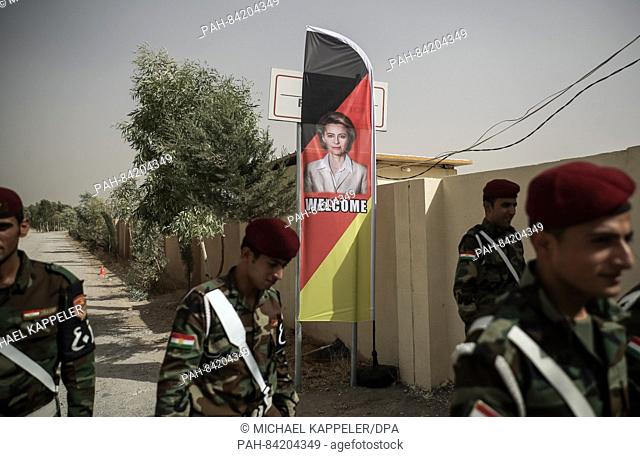 Kurdish Peshmerga soldiers stand in front of a banner with a picture of German Defense Minsiter Ursula von der Leyen in the Bnaslawa training center near Erbil