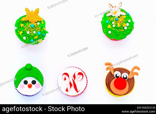New Year cupcakes made in shape of snowman, deer and christmas candies. Over white background, Copy space