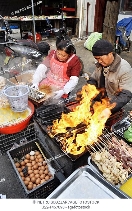 Shanghai (China): a couple cooking skewers at a street market by the Yuyuan Bazaar, in the Old Town