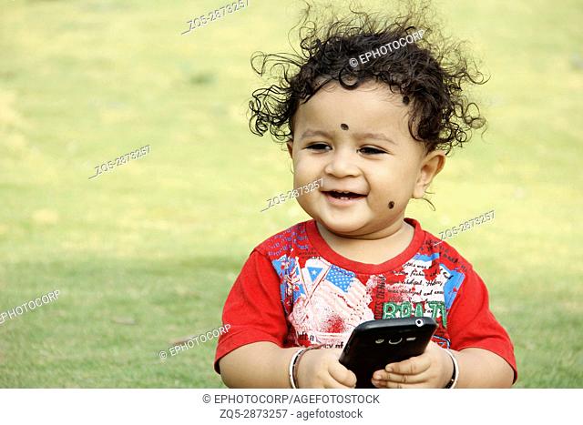 Little child with mobile in hand looking and smiling