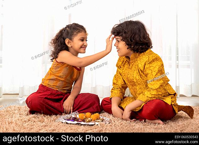 Little Girl applying tika on forehead of her brother on the occasion of Bhai Dooj