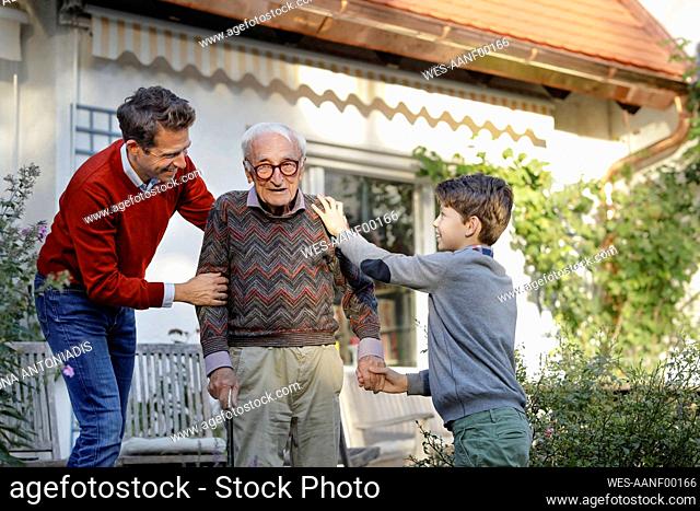 Smiling man with son consoling father in backyard