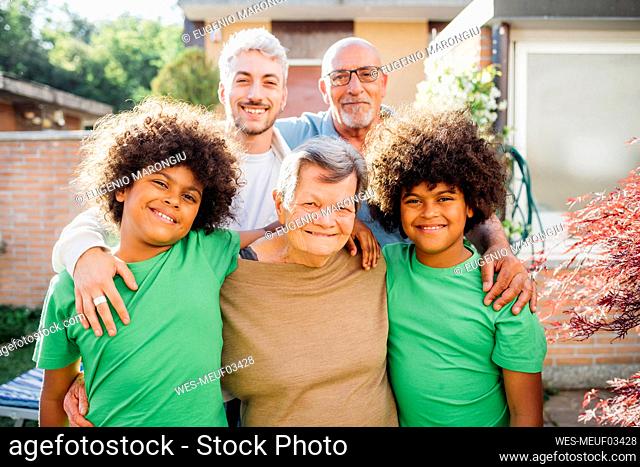 Smiling multi-ethnic family with arms around standing in back yard