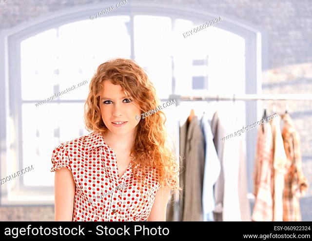 Young attractive female fashion designer working in office at desk smiling