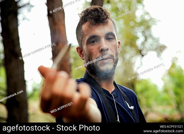 Young man with marijuana joint in forest