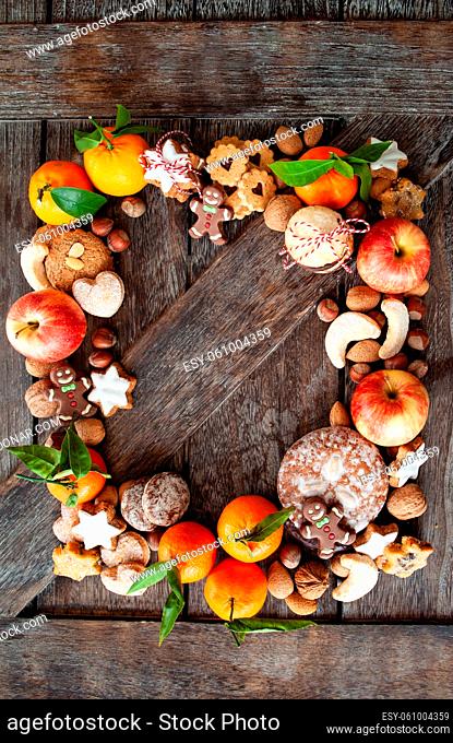 Lebkuchen , Nuesse und Fruechte zu Weihnachten auf rustikalem Hintergrund aus Holz