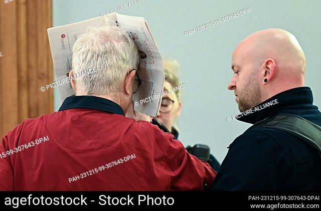 15 December 2023, Saxony, Leipzig: The accused is led into the courtroom by a court official. Six months after the brutal killing of a woman in Borna