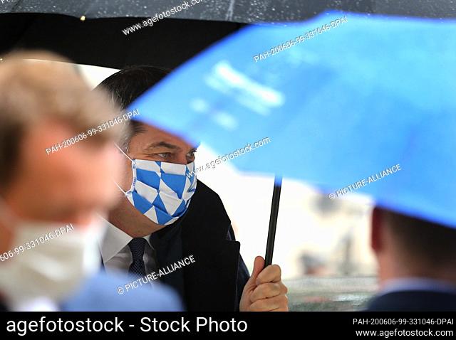 06 June 2020, Bavaria, Augsburg: Markus Söder (CSU), Bavarian Prime Minister, is standing in front of the cathedral with umbrella and face mask at the beginning...