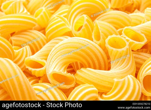 ellow background of pasta in the form of tubes spun in a spiral