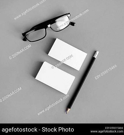 Blank stationery template on gray paper background. Business cards, pencil and glasses. For design presentations and portfolios. Flat lay