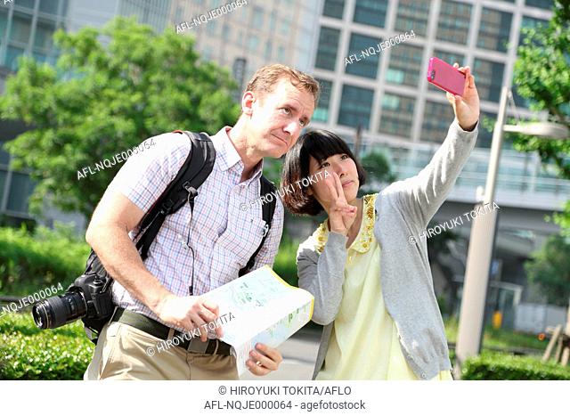 Young Japanese girl taking selfie with foreign tourist