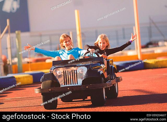 Young girls riding in electric toy car in a coastal region on a sunny day